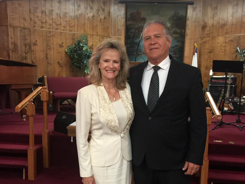 A man and woman standing in front of chairs.