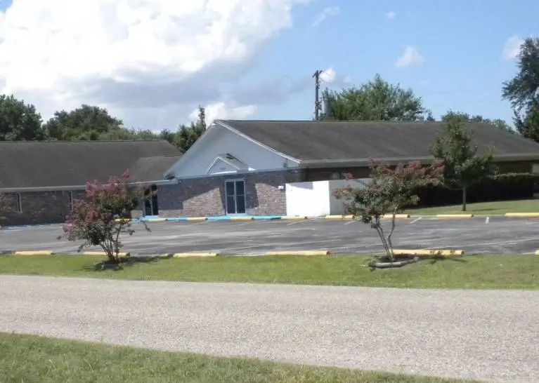 A church with trees and bushes in front of it.